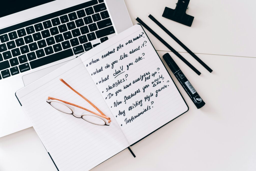 Organized workspace with laptop, notebook, and glasses, perfect for planning and strategy.